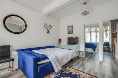 a bedroom with a blue bed and a mirror at Bright 2-Bed in Wimbledon - 3 min Walk to Tube in London