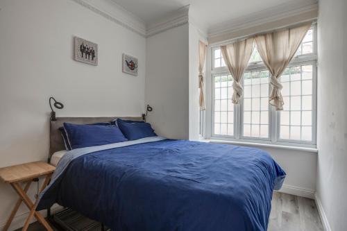 a bedroom with a blue bed and a window at Bright 2-Bed in Wimbledon - 3 min Walk to Tube in London