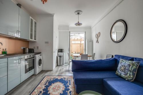 a living room with a blue couch and a kitchen at Bright 2-Bed in Wimbledon - 3 min Walk to Tube in London
