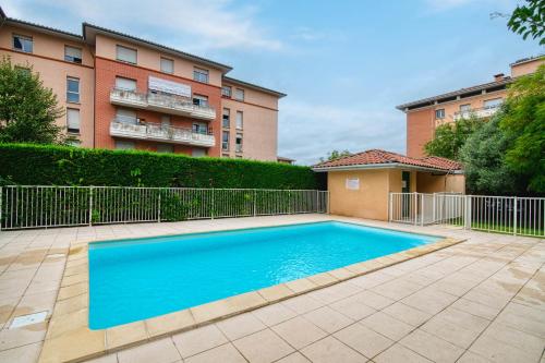 a swimming pool in front of a building at L'Arène de coeur - appt avec piscine partagée in Toulouse
