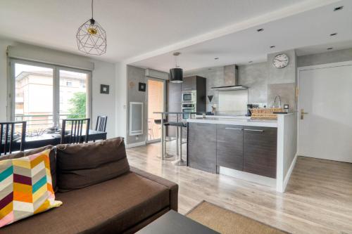 - un salon et une cuisine avec un canapé et un comptoir dans l'établissement L'Arène de coeur - appt avec piscine partagée, à Toulouse