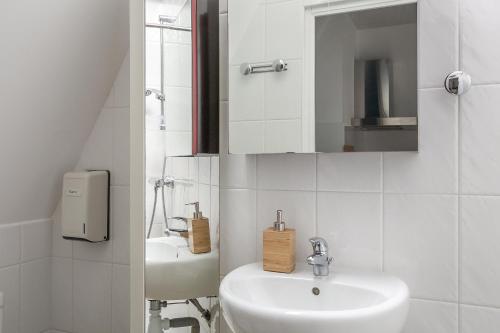 une salle de bain blanche avec un lavabo et un miroir dans l'établissement La Cabane Malouine, à Saint-Malo