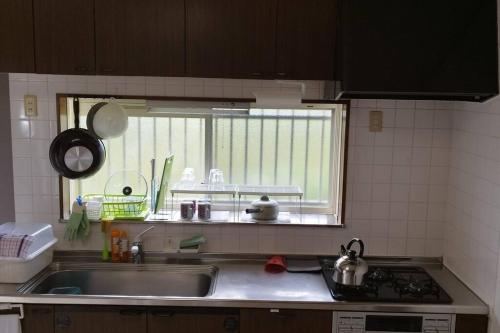 a kitchen counter with a sink and a window at はうす41マイルズ in Katakai