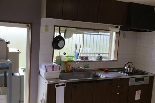 a kitchen with a sink and a window at はうす41マイルズ in Katakai