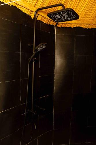 a shower in a black tiled bathroom at Olemayian Amboseli Cottages in Kimana