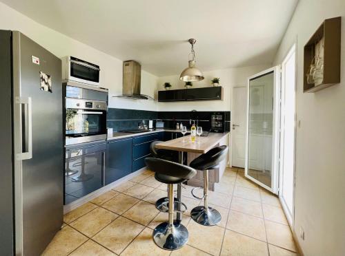 une cuisine avec des placards bleus, une table et deux tabourets dans l'établissement La villa Louca, à Saint-Saturnin-lès-Apt
