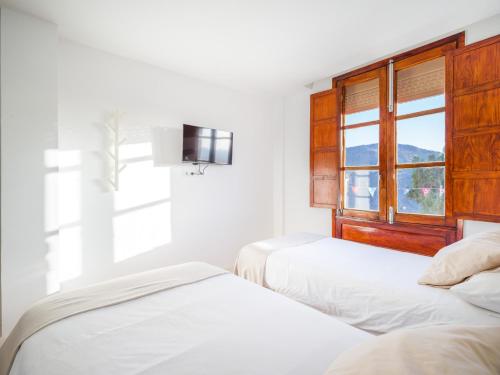 two beds in a white room with a window at Texeda Room Suites in Tejeda