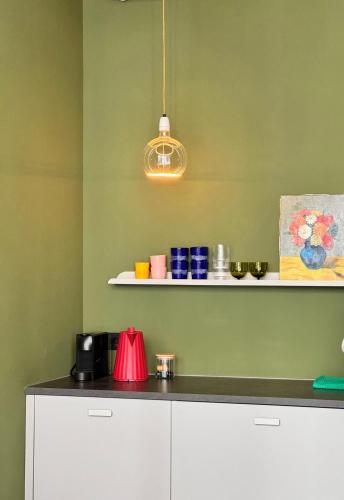 a kitchen with green walls and a counter with a light at Daen’s Greenhouse in Utrecht