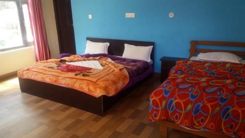 a bedroom with two beds and a blue wall at Vamoose Maa Bhawani Munsiyari in Munsyari