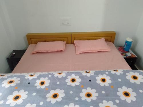 a bed with a pink bedspread with flowers on it at Vamoose Maa Bhawani Munsiyari in Munsyari