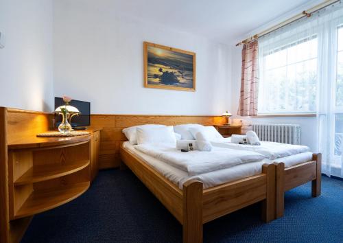 a bedroom with two beds and a desk and a window at Hotel Horník in Žďár nad Sázavou