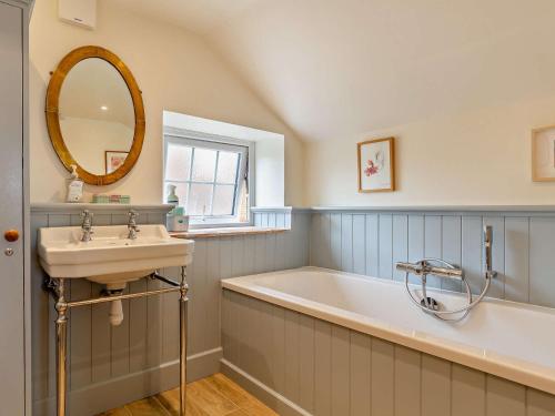 a bathroom with a sink and a tub and a mirror at 3 Bed in Charmouth 93420 in Charmouth
