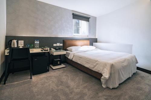 a bedroom with a bed and a desk with a phone at Hotel Puri in Taipei