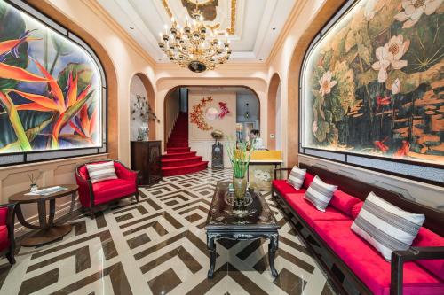 a living room with a red couch and a chandelier at Hanoi Little Town Hotel in Hanoi