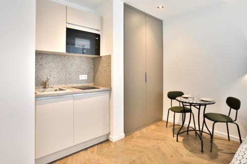 une cuisine avec une table, des chaises et un évier dans l'établissement Le carré central A Mulhouse, à Mulhouse