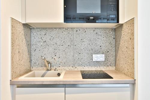 une cuisine avec un évier et un micro-ondes dans l'établissement Le carré central A Mulhouse, à Mulhouse