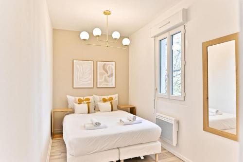 une chambre avec un grand lit blanc et un miroir dans l'établissement Appartement lumineux proche de Paris, à Asnières-sur-Seine