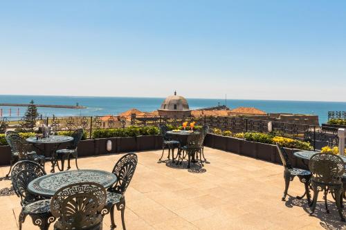 an outdoor patio with tables and chairs and the ocean at Hotel Boa - Vista in Porto