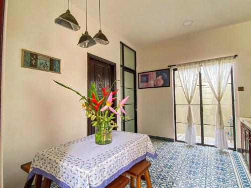 a dining room with a table with a vase of flowers at DƯỚI TÁN CÂY homestay in Tây Ninh