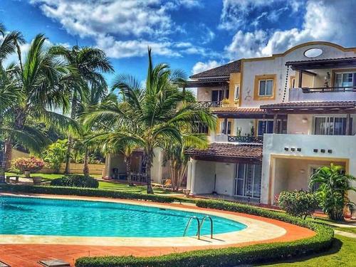 a swimming pool in front of a house with palm trees at Tamarindo in Bayahibe