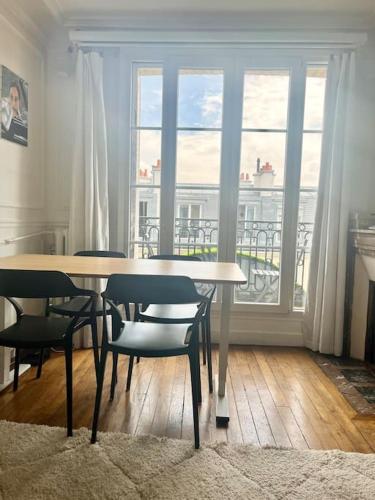 une salle à manger avec une table et des chaises et une fenêtre dans l'établissement Appartement de charme, terrasse et vue Tour Eiffel, à Paris