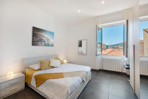 a white bedroom with a bed and a large window at Casa Alba La Casa Delle Coccole in Savona
