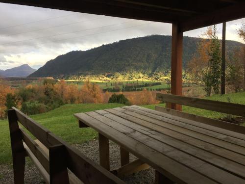 a wooden bench on a porch with a view of a mountain at Cabañas Futrono in Futrono