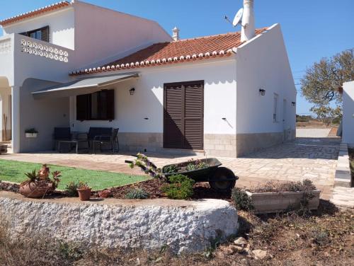 a white house with a wheelbarrow in front of it at Casa Raios de Sol in Burgau