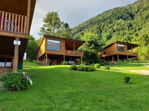 two houses on a lawn with mountains in the background at Cabañas Futrono in Futrono