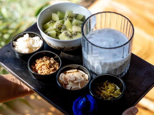 Una bandeja con cuencos de comida y un cuenco de fruta. en Dejama Glamping Resort Lombok, en Bumbang