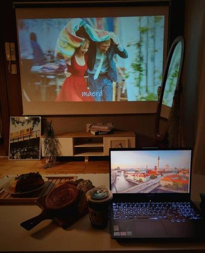 a laptop computer sitting on a desk with a television at Henzel House - 2min to Yongmun Station, 5mins to Seongsimdang in Daejeon