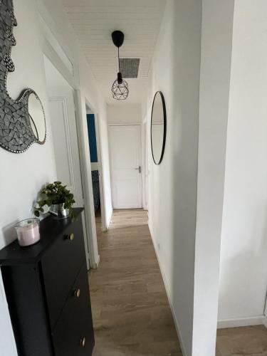un couloir avec une commode noire et deux miroirs dans l'établissement Bright T3 200m from the beach close to shops, à Antibes