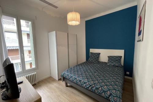 une chambre avec un lit et un mur bleu dans l'établissement Bright T3 200m from the beach close to shops, à Antibes
