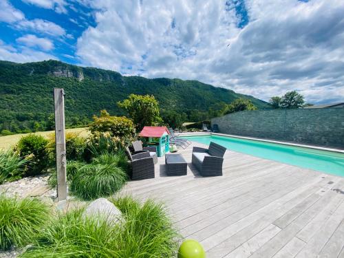 a pool with chairs and a table on a wooden deck at Villa des 3 fontaines in Annecy