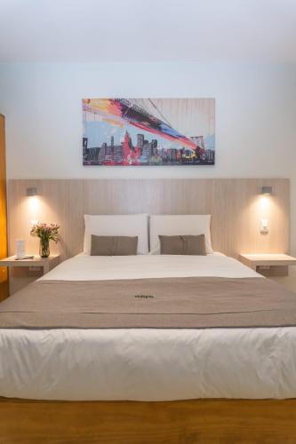 a bedroom with a large white bed with a painting on the wall at ELDEPTO Parque Bustamante in Santiago