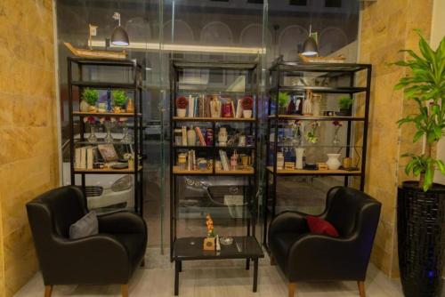 a room with two chairs and a book shelf at فندق كروان جده in As Salamah