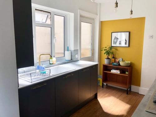 a kitchen with a sink and two windows at Flat1Hove- renovated, 2BR, patio, beach, free onsite parking in Hove