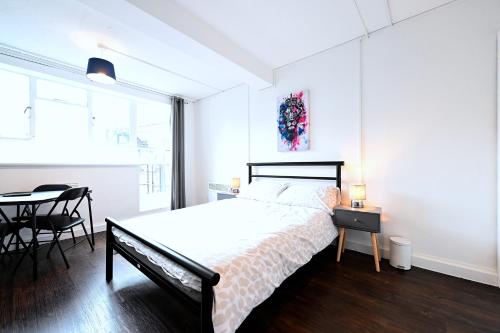 ein weißes Schlafzimmer mit einem Bett und einem Esstisch in der Unterkunft Centrally located flat in Leicester Square in London