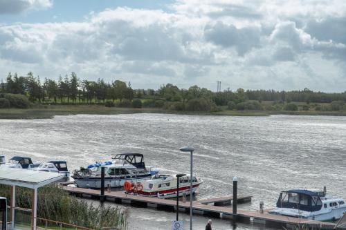 a group of boats docked at a dock on a river at Waterfront View Apartment in Carrick on Shannon