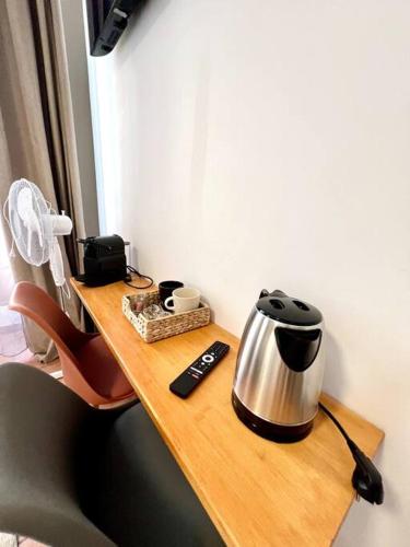 - une table en bois avec une bouilloire et une télécommande dans l'établissement Les chambres de la bastide - 105, à Carcassone
