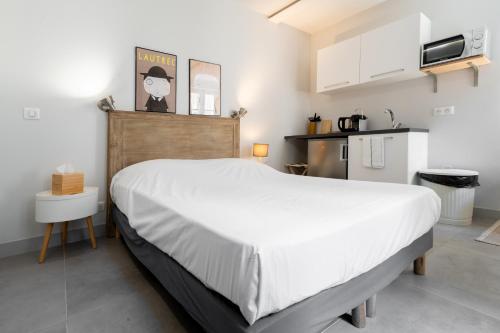 a bedroom with a large white bed and a kitchen at Apparts de l'Oncle Louis in Versailles