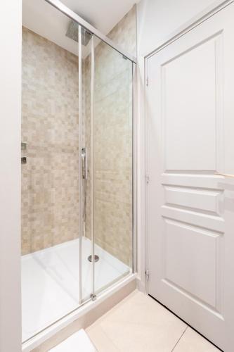 a shower with a glass door in a bathroom at Apparts de l'Oncle Louis in Versailles