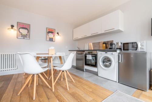 a kitchen with stainless steel appliances and a table with white chairs at Apparts de l'Oncle Louis in Versailles