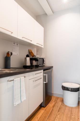 a kitchen with white cabinets and a wooden floor at Apparts de l'Oncle Louis in Versailles