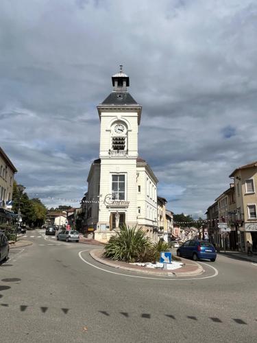 a building with a clock tower in the middle of a street at Les Galamières in Meximieux