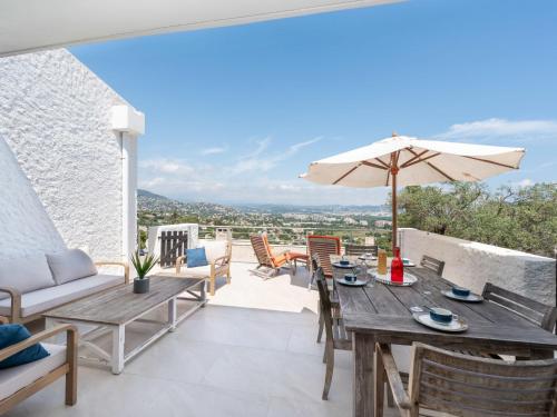 une terrasse avec une table et des chaises en bois ainsi qu'un parasol dans l'établissement Holiday Home Domaine de Maure Vieil by Interhome, à La Napoule-Plage