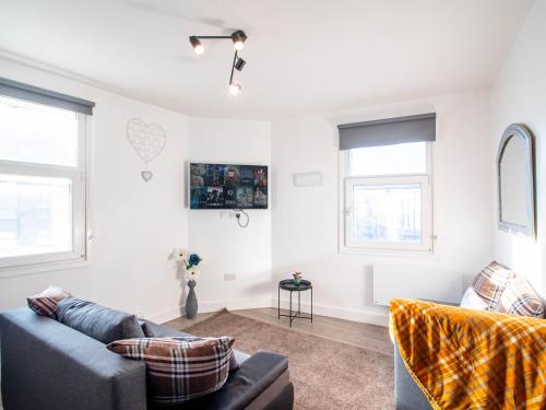 a living room with a couch and two windows at The heart of Huddersfield hideaway in Huddersfield