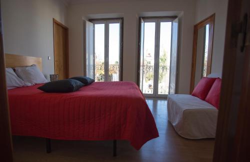 a bedroom with a bed with a red blanket and windows at Casas do Terreiro in Seia