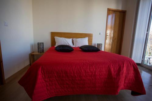 a bedroom with a red bed with two pillows on it at Casas do Terreiro in Seia