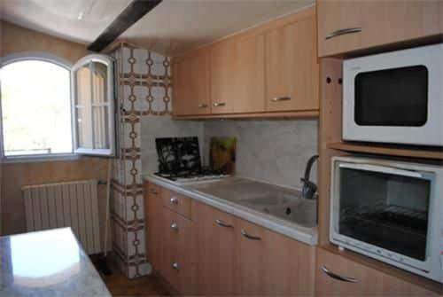 - une cuisine avec des placards en bois et un four micro-ondes dans l'établissement T2 vue sur le château Gréoux, à Gréoux-les-Bains